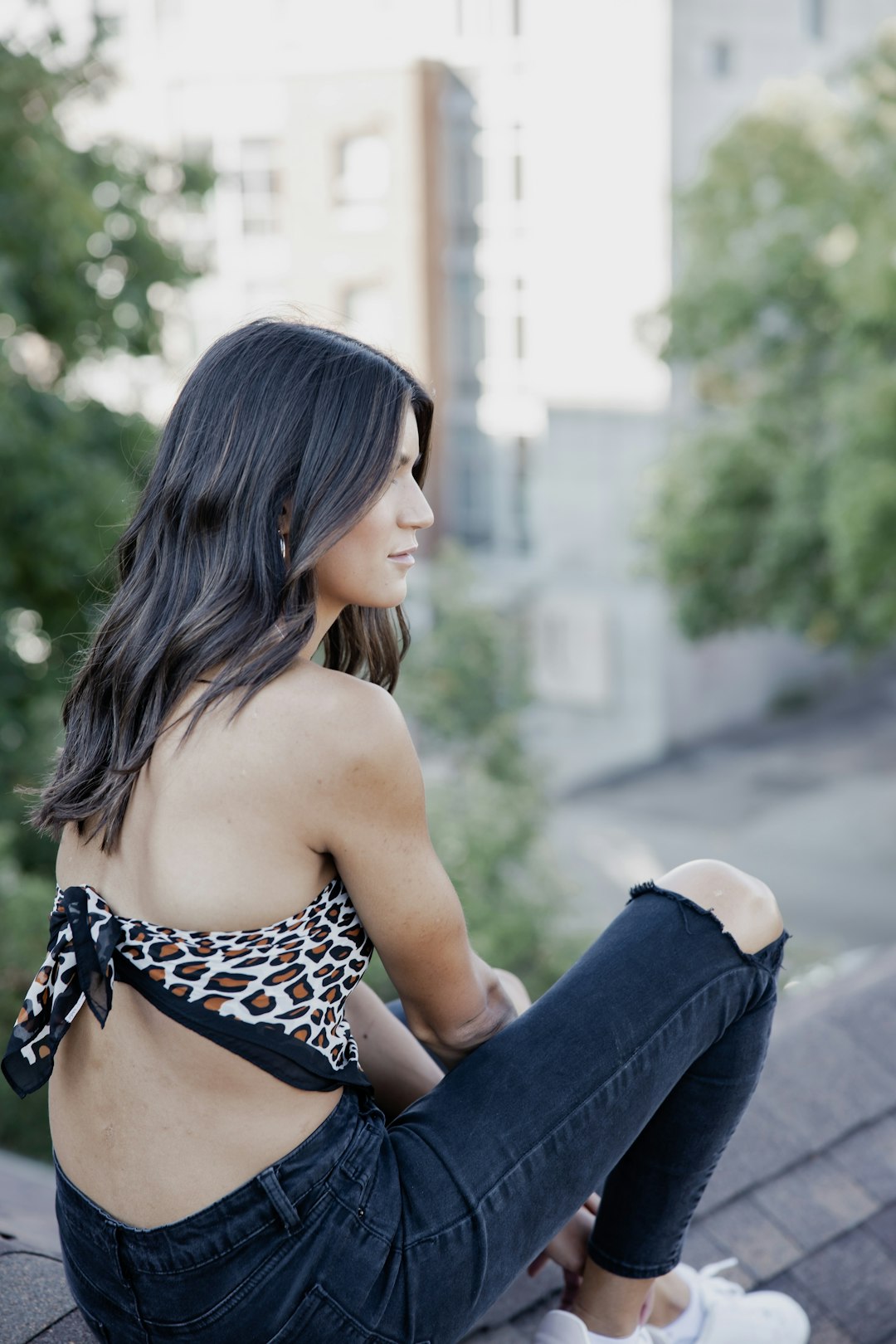 woman in black and white leopard print bikini top and blue denim jeans sitting on gray