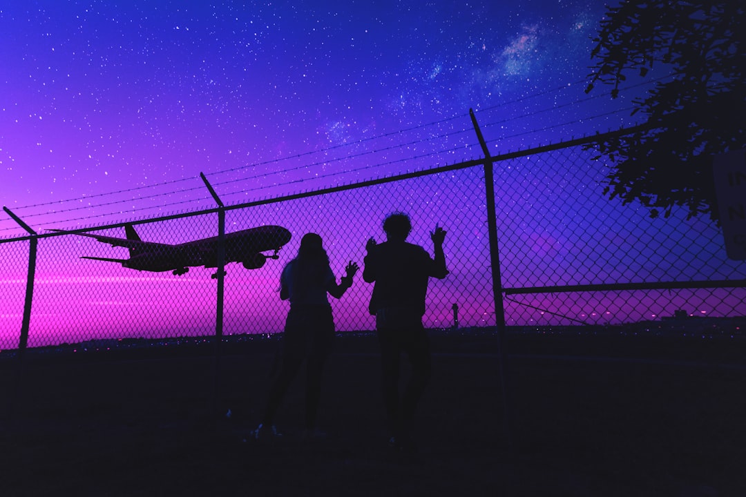 silhouette of 2 person standing beside fence during night time