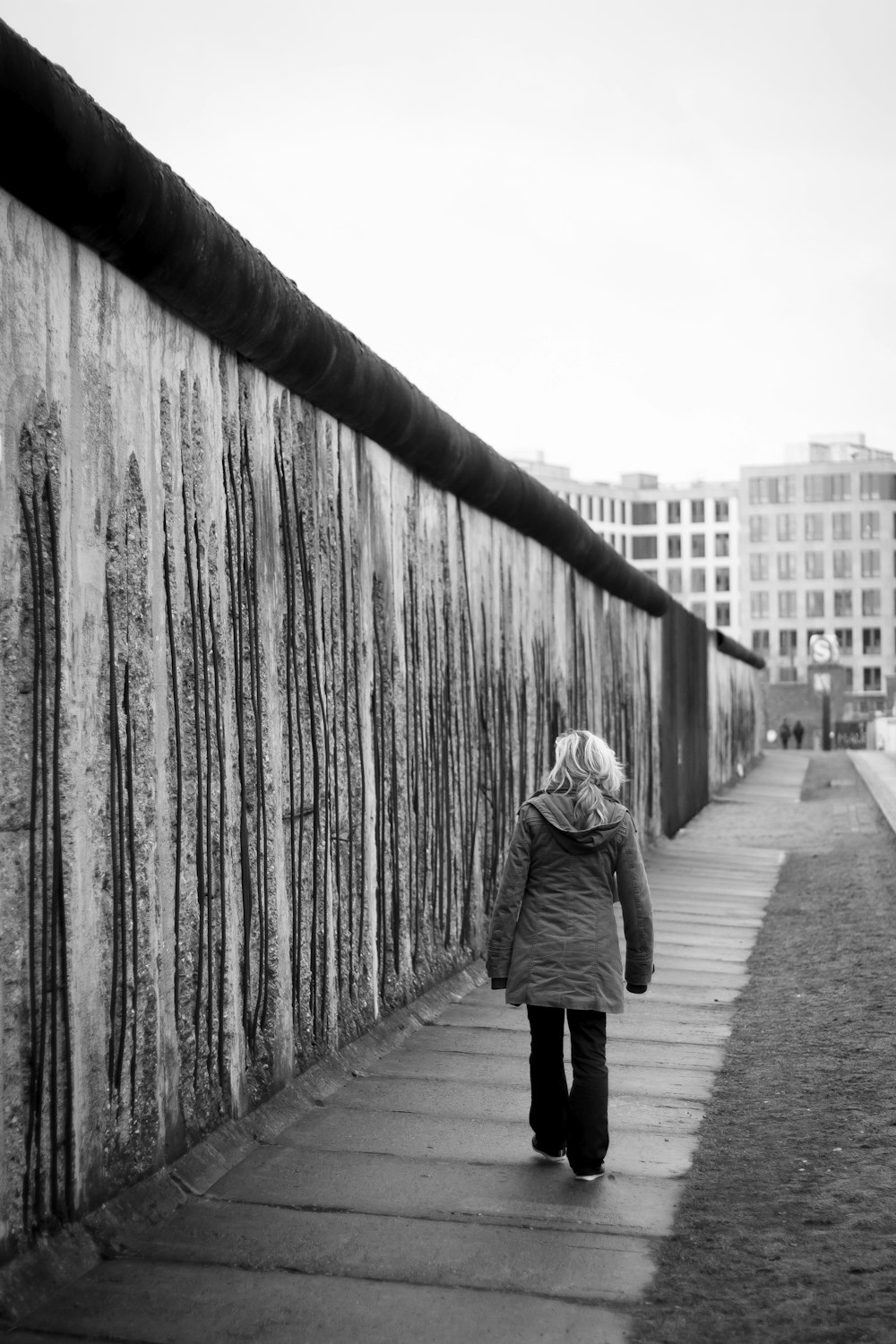 grayscale photo of woman walking on sidewalk