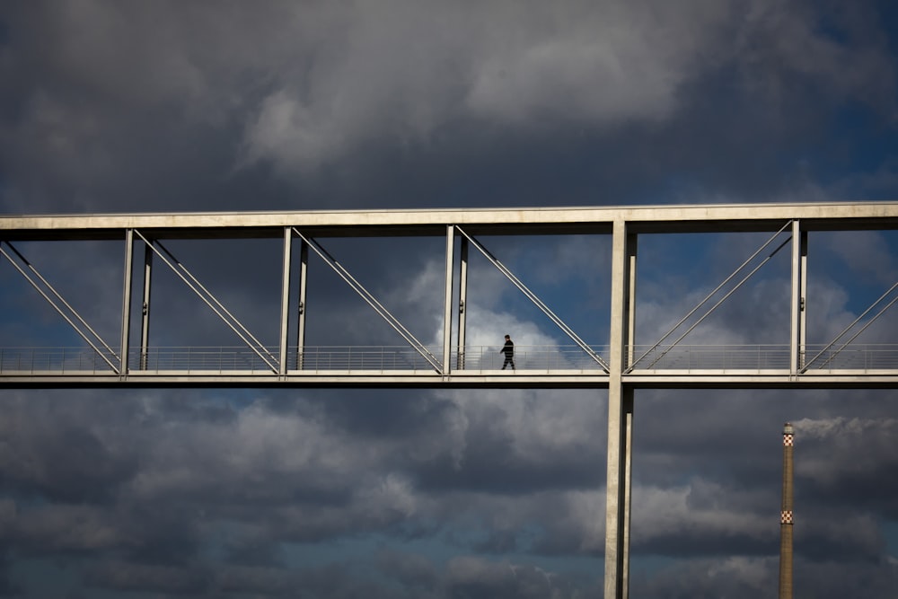 gray metal bridge under gray clouds