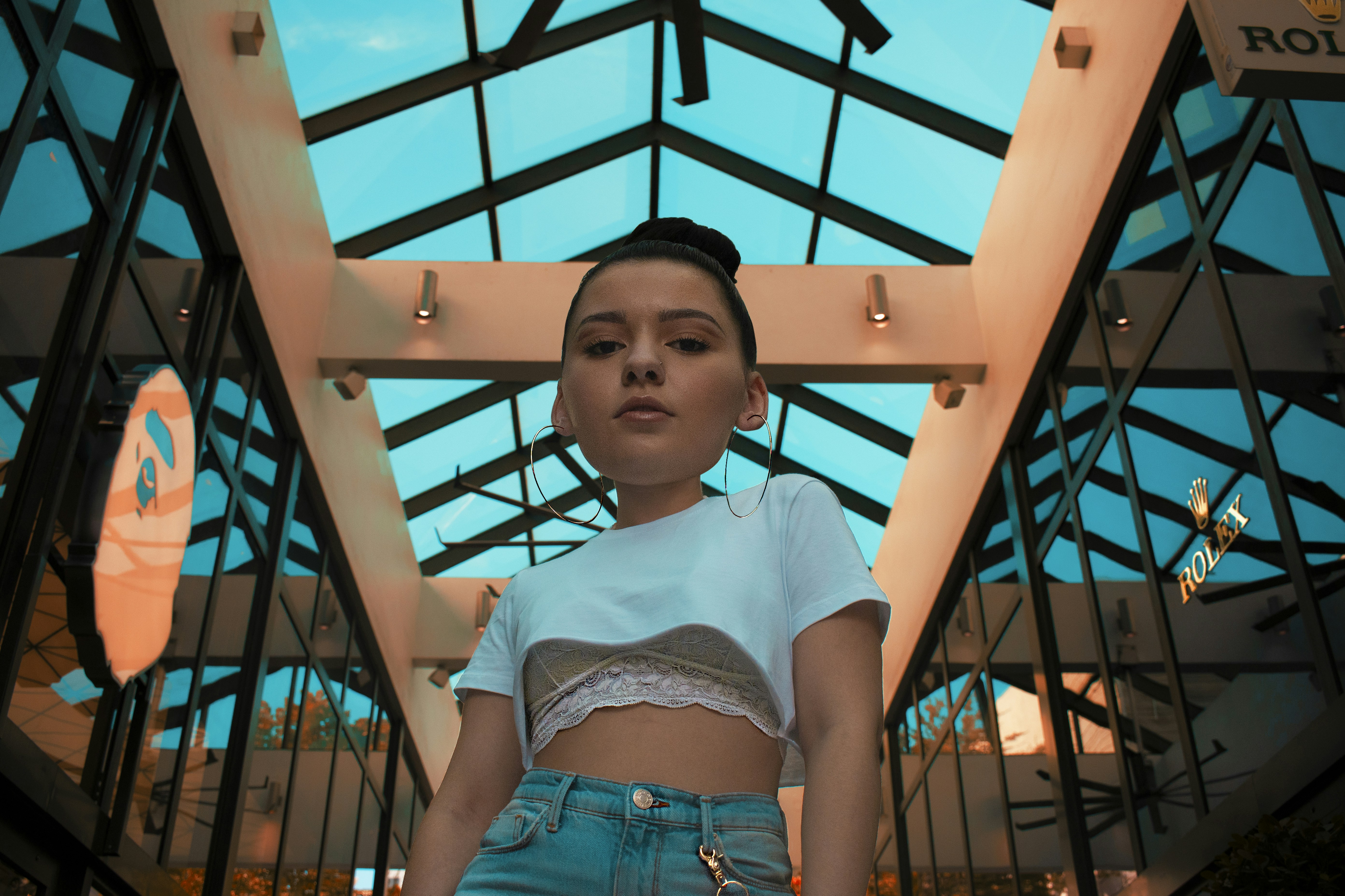 woman in white shirt and blue denim shorts standing near blue metal frame