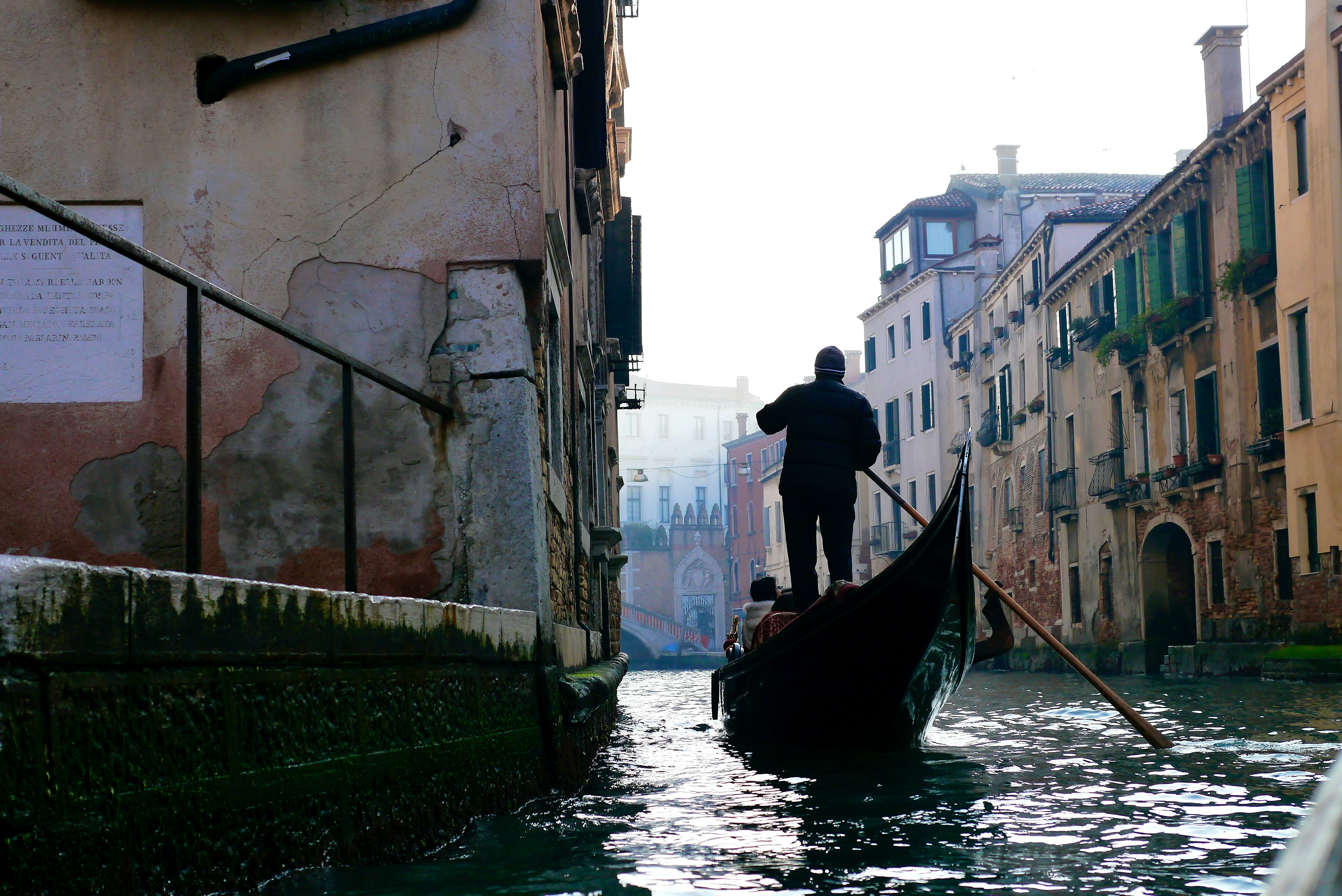 black boat on river between concrete buildings during daytime