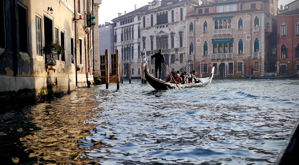 people riding on boat on river between buildings during daytime