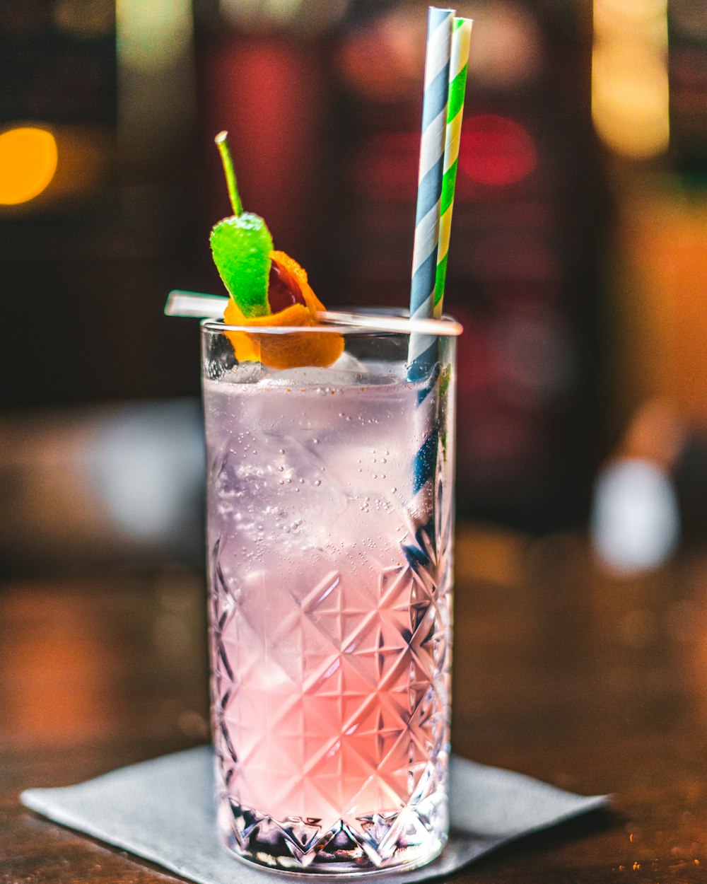 clear drinking glass with pink liquid and green straw