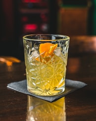 clear drinking glass with yellow liquid on brown wooden table