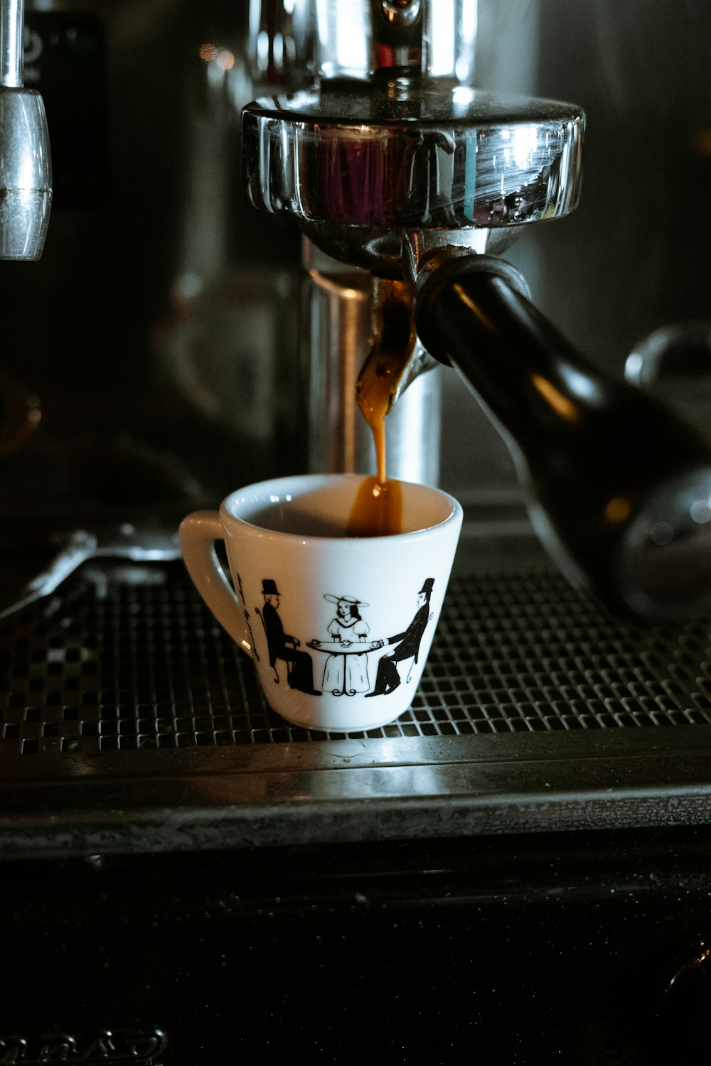 white and black ceramic mug on black and silver coffee maker