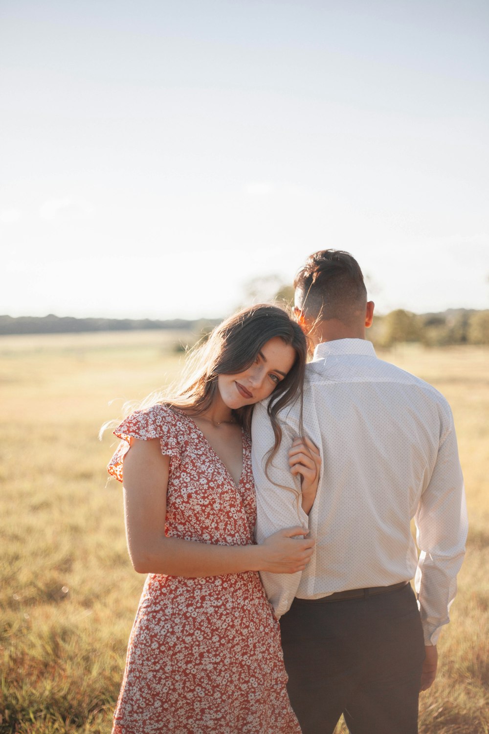 man in white dress shirt kissing woman in red and white floral dress