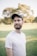 man in white crew neck shirt wearing black cap standing on green grass field during daytime