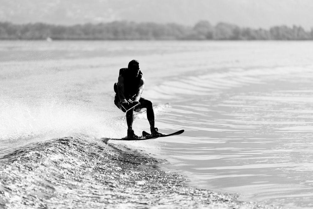 man in black jacket riding on surfboard on body of water