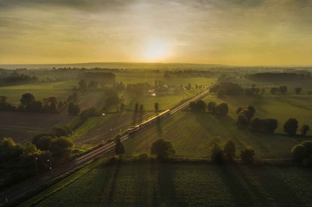 aerial view of road between green grass field during daytime