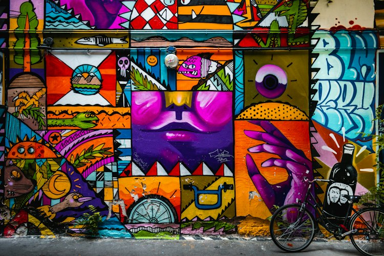 A traveler with a map and phone strolling past colorful street murals in a historic city neighborhood