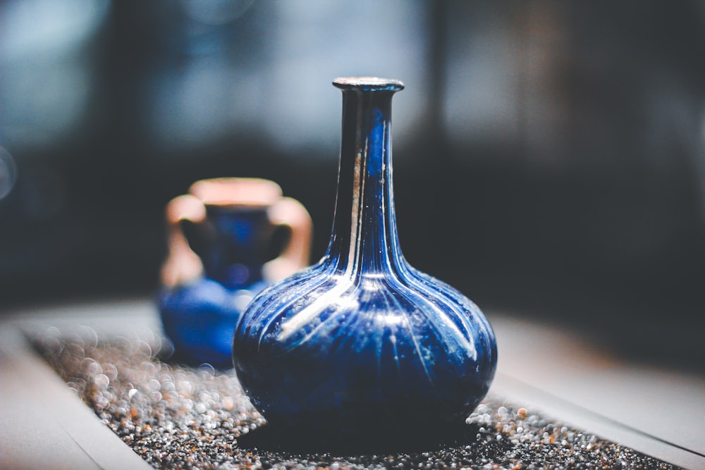 blue glass vase on brown and black marble table