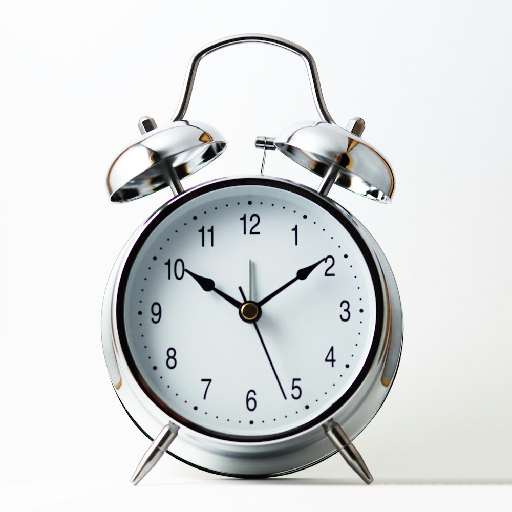 silver and white analog alarm clock