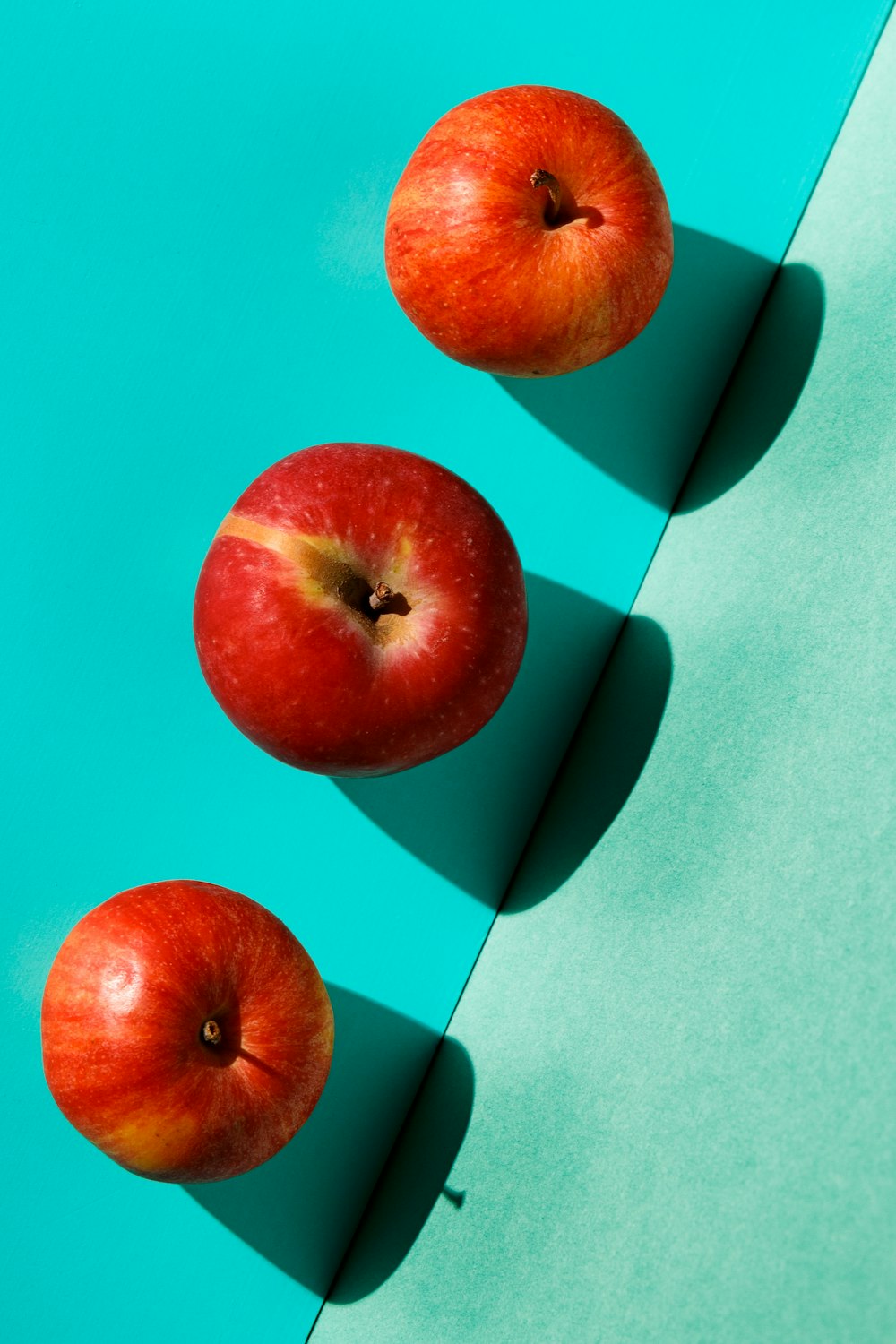 red apple fruit on teal surface
