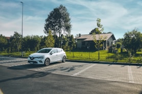 A family smiling next to their new car parked outside their home
