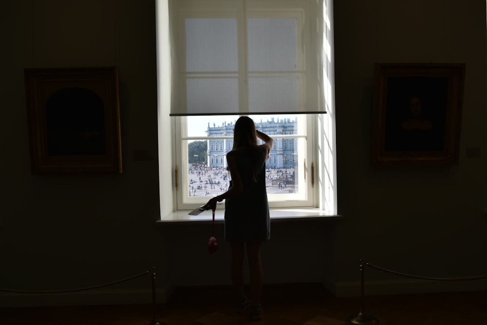 woman in black dress standing by the window