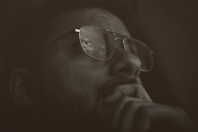 A close-up portrait of a young person wearing augmented reality glasses, looking thoughtfully into the distance.