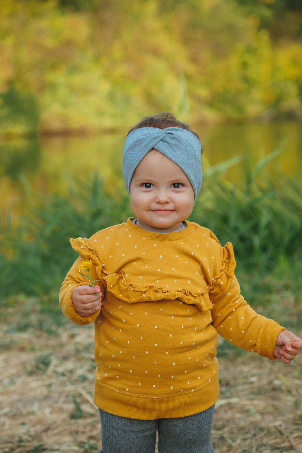 girl in yellow and white polka dot long sleeve shirt standing near body of water during