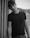 Portrait of a young man with casual streetwear, shot in black and white against a plain wall.