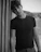 Portrait of a young man with casual streetwear, shot in black and white against a plain wall.