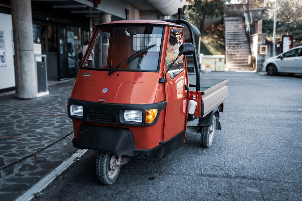 Volkswagen T-2 rossa e nera parcheggiata su un marciapiede di cemento grigio durante il giorno