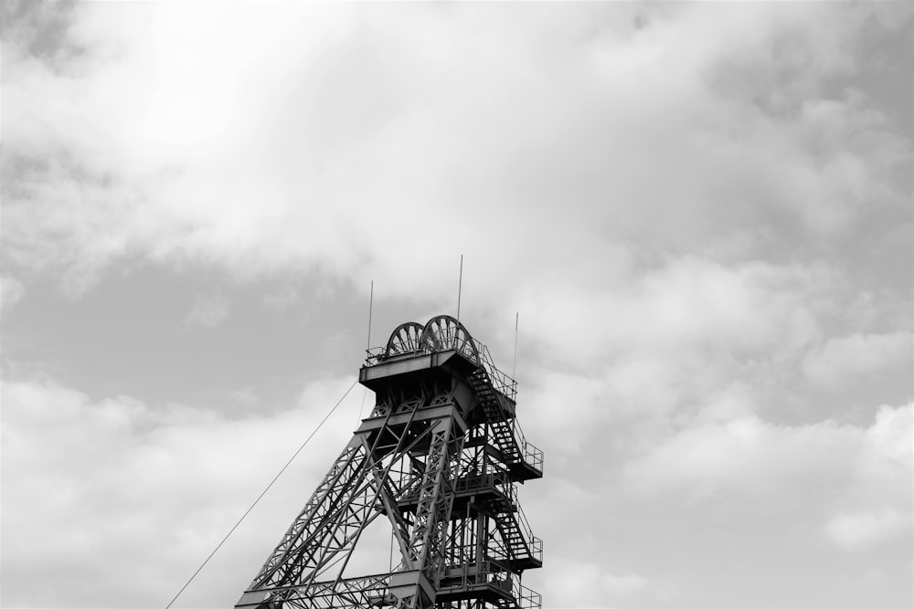 grayscale photo of tower under cloudy sky