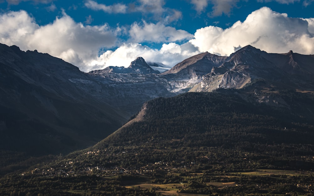 montanhas marrons e brancas sob céu azul e nuvens brancas durante o dia