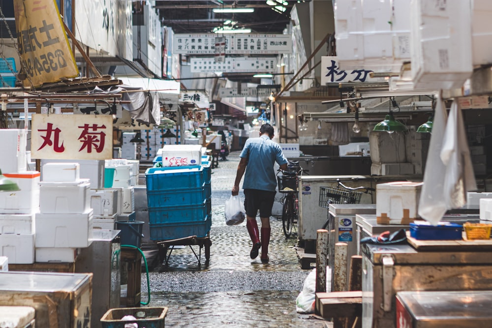 Uomo in camicia blu e pantaloni neri che camminano sulla strada durante il giorno