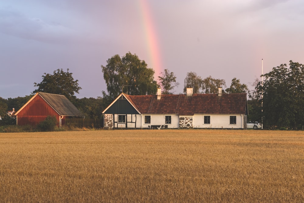 Weißes und braunes Haus in der Nähe von grünem Grasfeld tagsüber