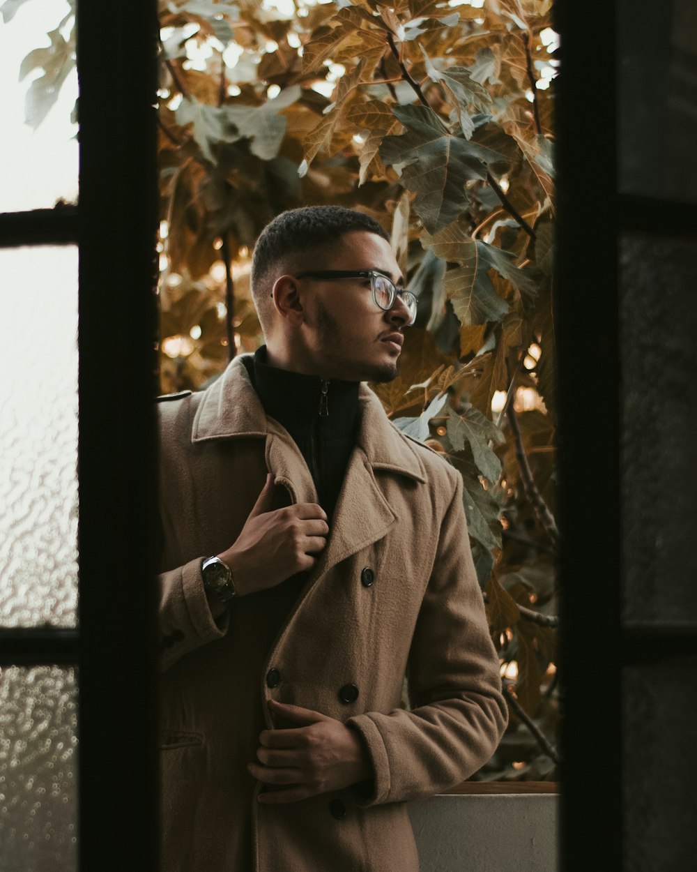 man in brown coat standing near green leaf tree during daytime