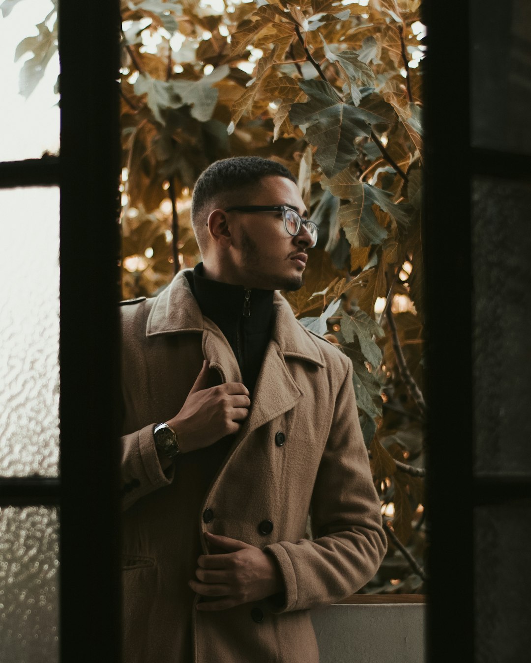 man in brown coat standing near green leaf tree during daytime