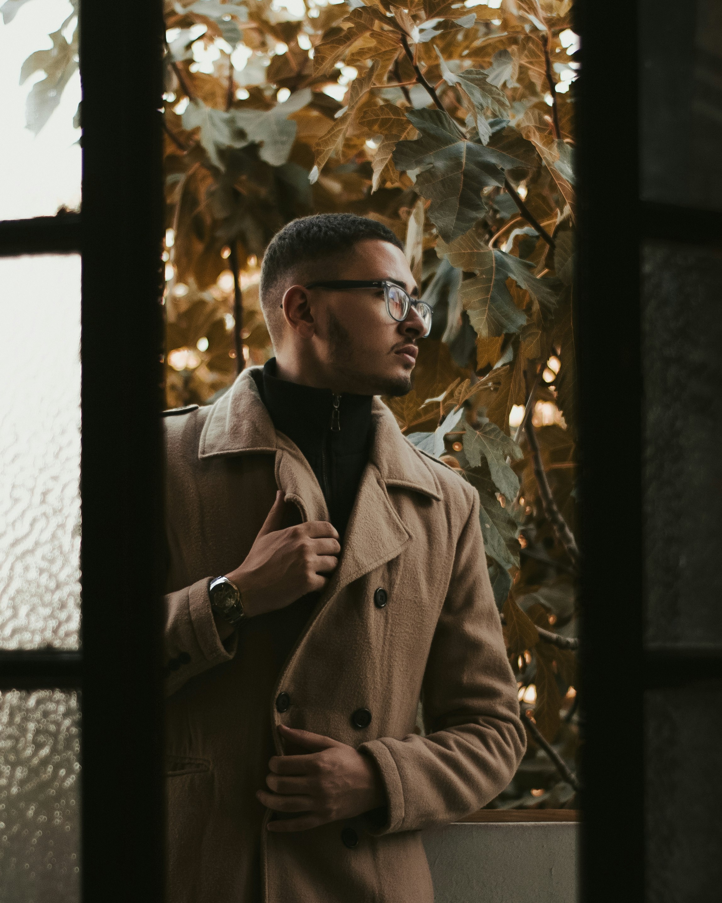 man in brown coat standing near green leaf tree during daytime