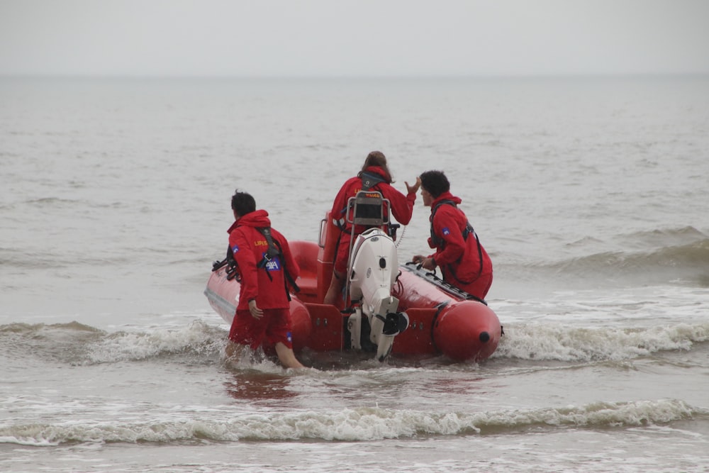 2 men in red life vest riding red inflatable boat on sea during daytime