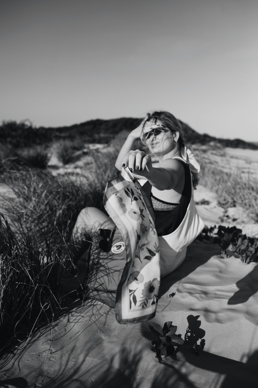 woman in black tank top and white shorts sitting on sand during daytime