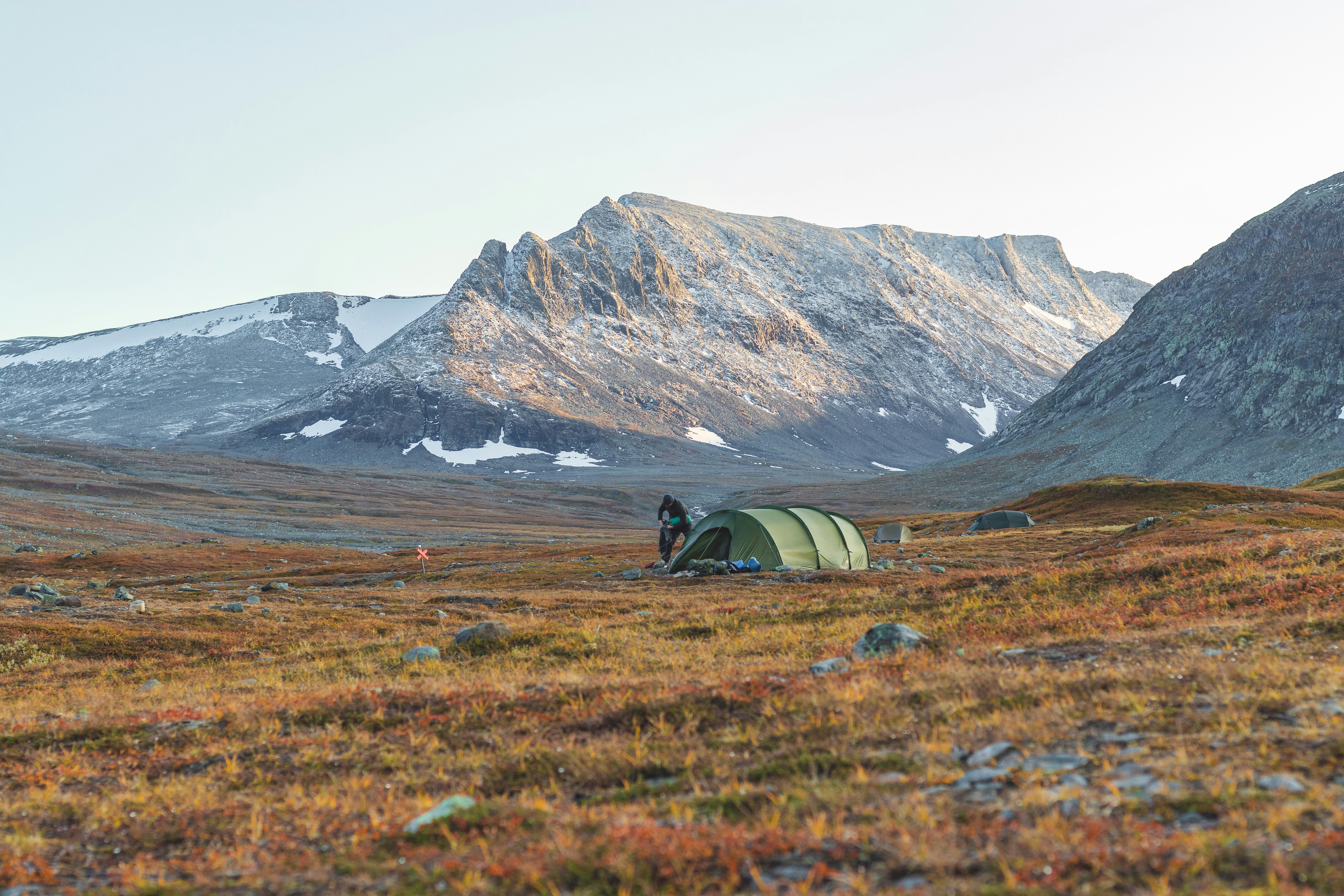 gray tent on green grass field near brown mountain during daytime