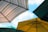 Four large outdoor umbrellas with different colors and patterns are opened against a clear blue sky. The umbrellas are positioned at various angles, and their shapes create a geometric pattern. The colors include striped patterns, green, and yellow.