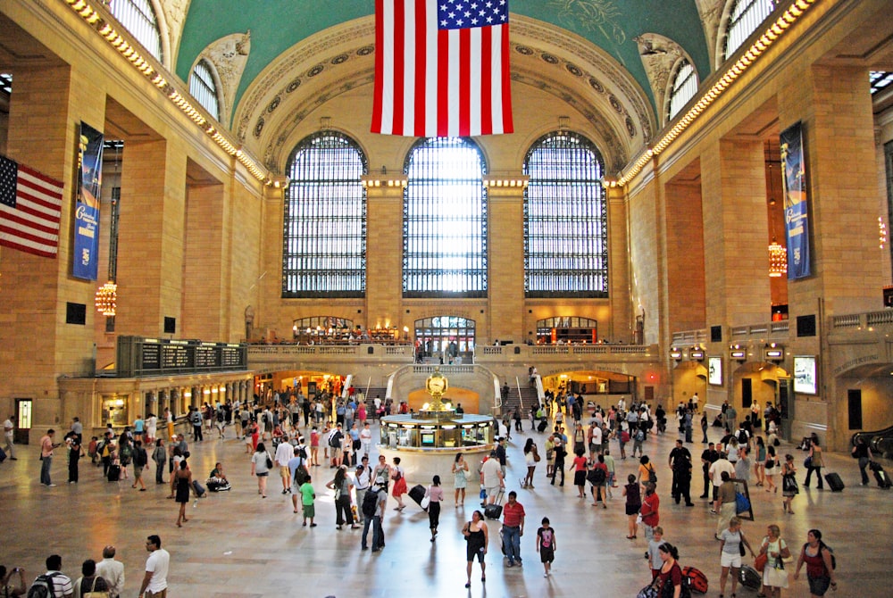 people walking inside building with american flag on top