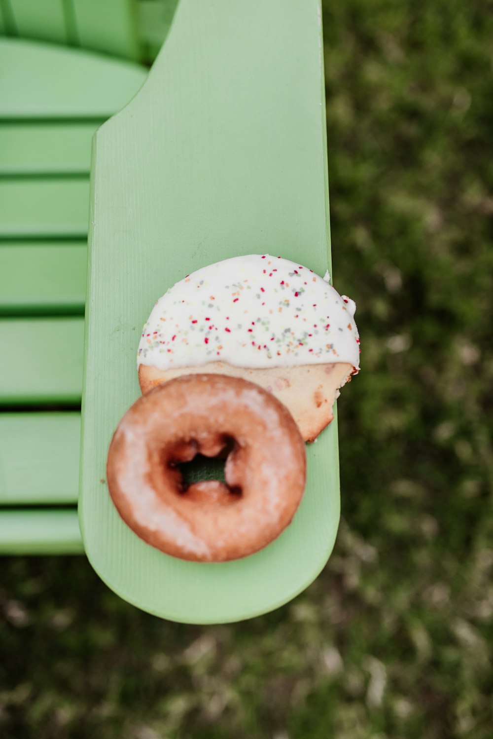 a half eaten doughnut sitting on top of a green bench
