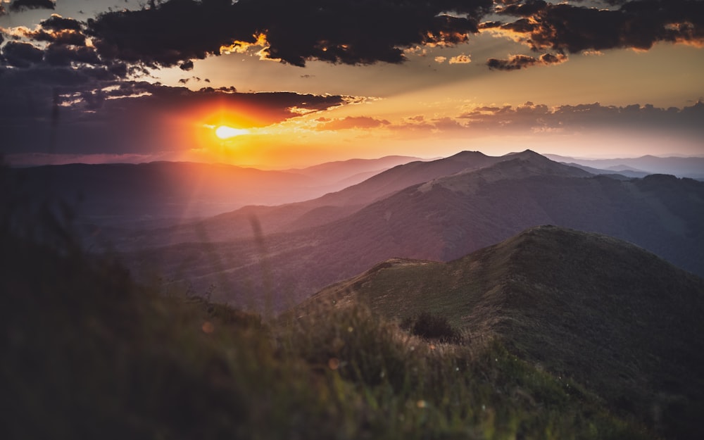 green grass field near mountain during sunset