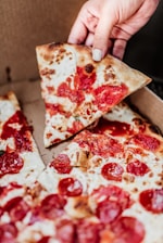 Close-up of a hand holding a delicious, freshly baked pizza box with steam rising.
