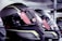 A close-up view of several high-tech motorcycle helmets arranged in a row. The helmets feature a sleek, aerodynamic design with a combination of glossy black and reflective yellow patterns. The visors have warning stickers indicating anti-scratch features, with text and symbols visible upon inspection.
