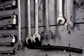 A friendly plumber in uniform holding a wrench, standing in front of a house.
