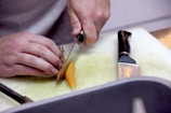 person holding yellow leaf on white chopping board