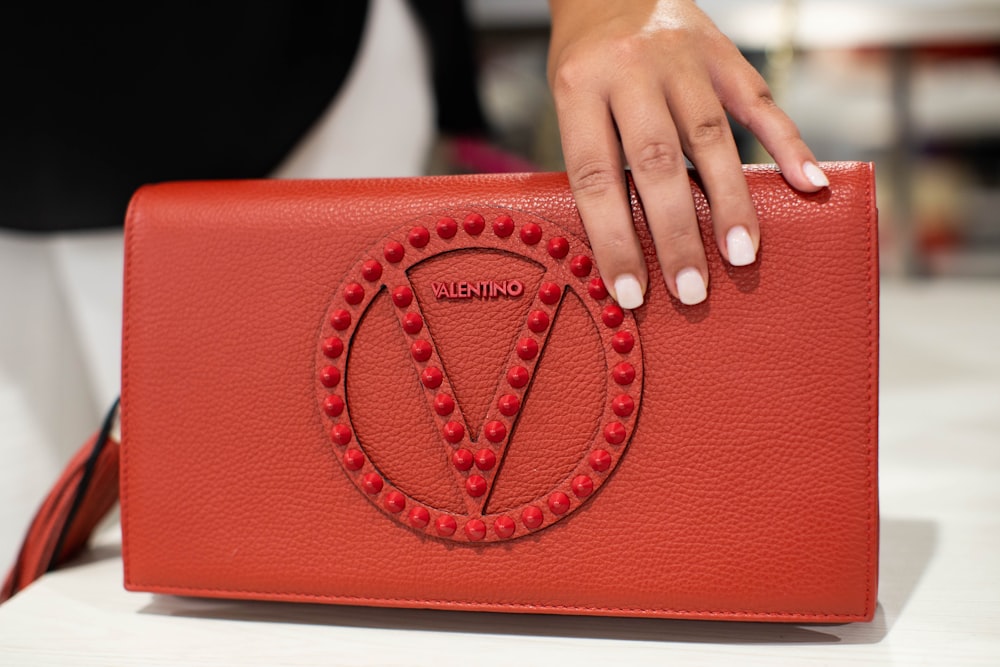 person holding red leather handbag