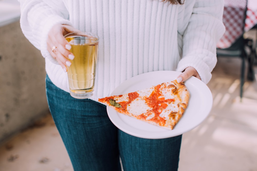 person holding white ceramic plate with pizza