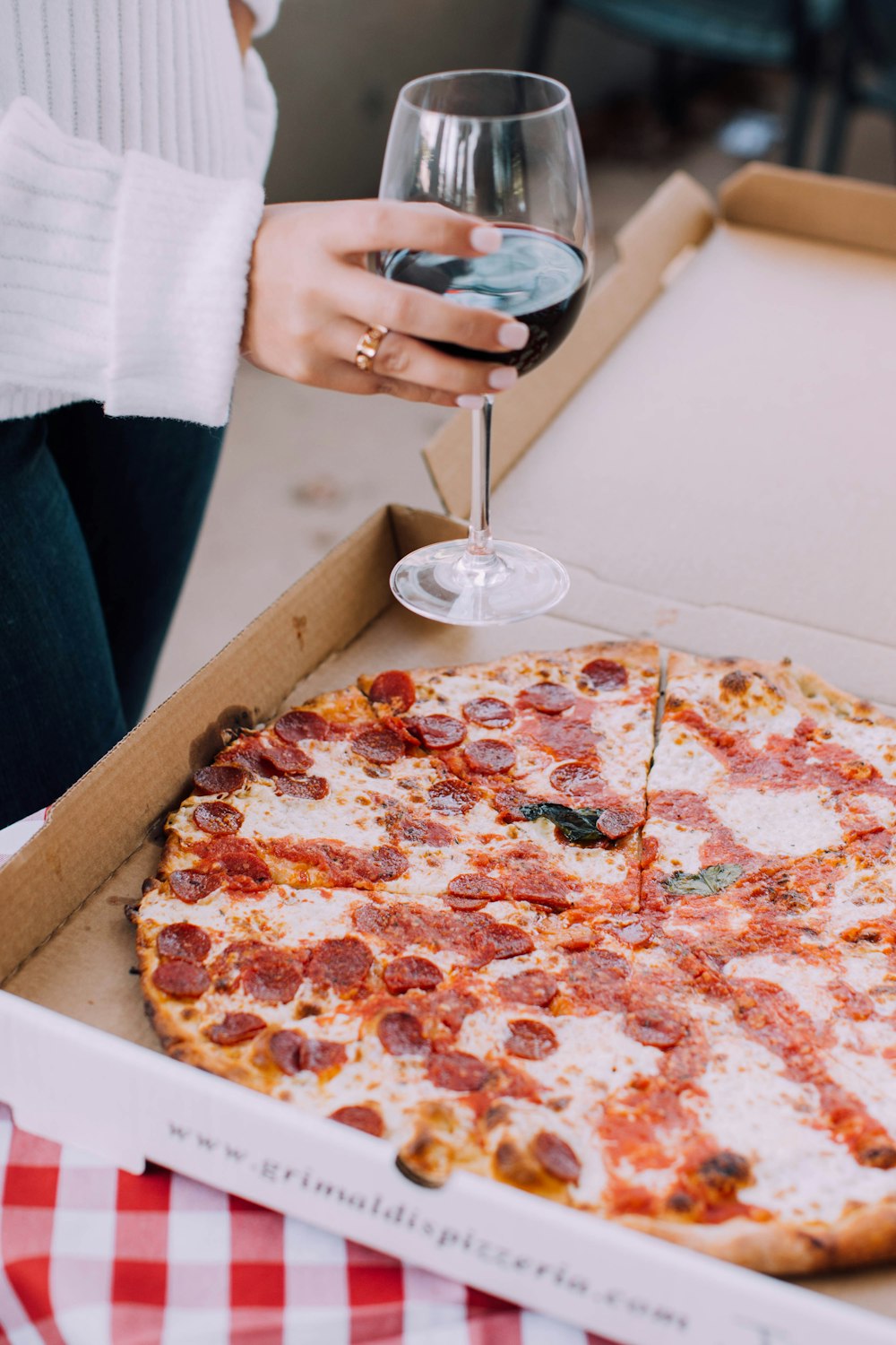 person holding pizza with pepperoni and cheese