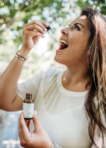 A serene scene of a person holding a dropper bottle with Bach flower remedies in a garden.