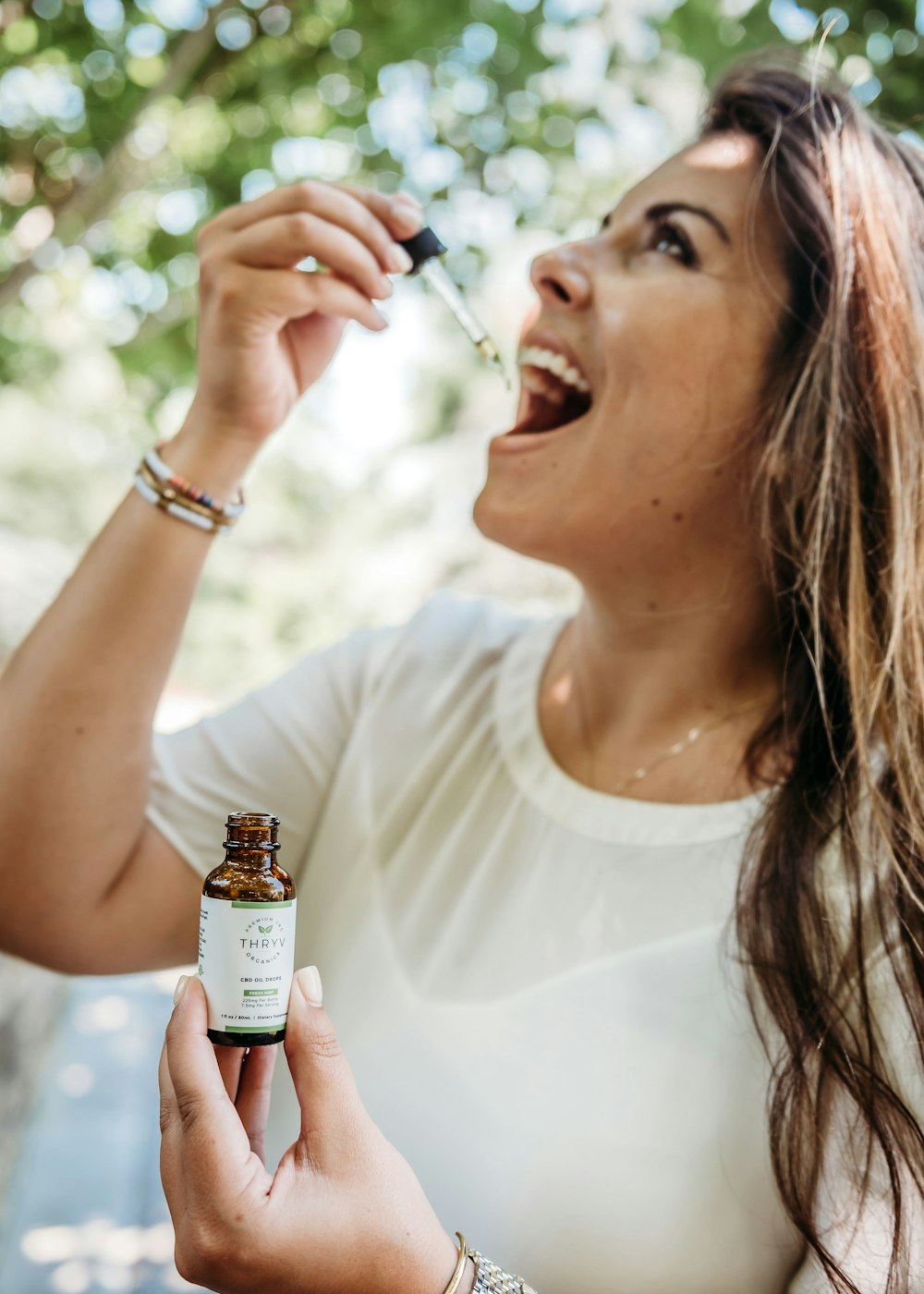 woman in white crew neck shirt holding brown glass bottle