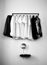white and black clothes hanging on black steel rack