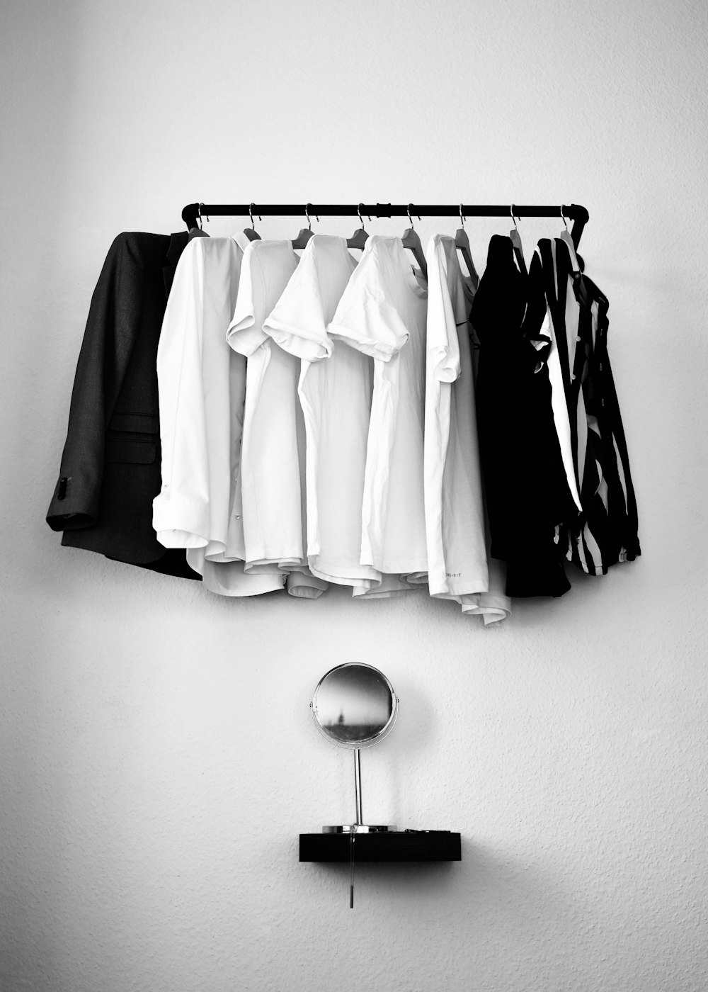 white and black clothes hanging on black steel rack